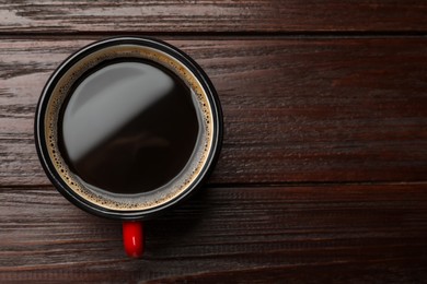 Photo of Cup of aromatic coffee on wooden table, top view. Space for text