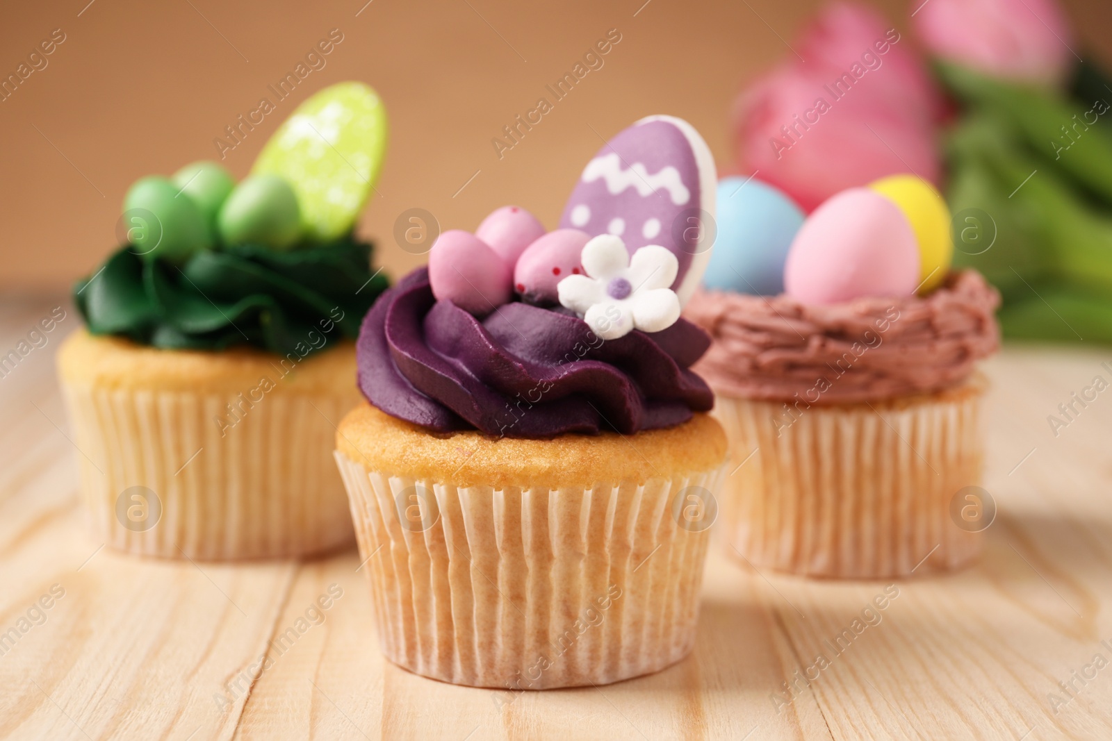 Photo of Tasty cupcakes with Easter decor on wooden table, closeup