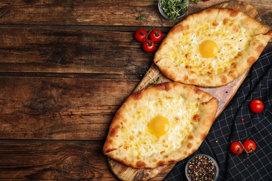 Photo of Fresh delicious Adjarian khachapuris served on wooden table, flat lay. Space for text