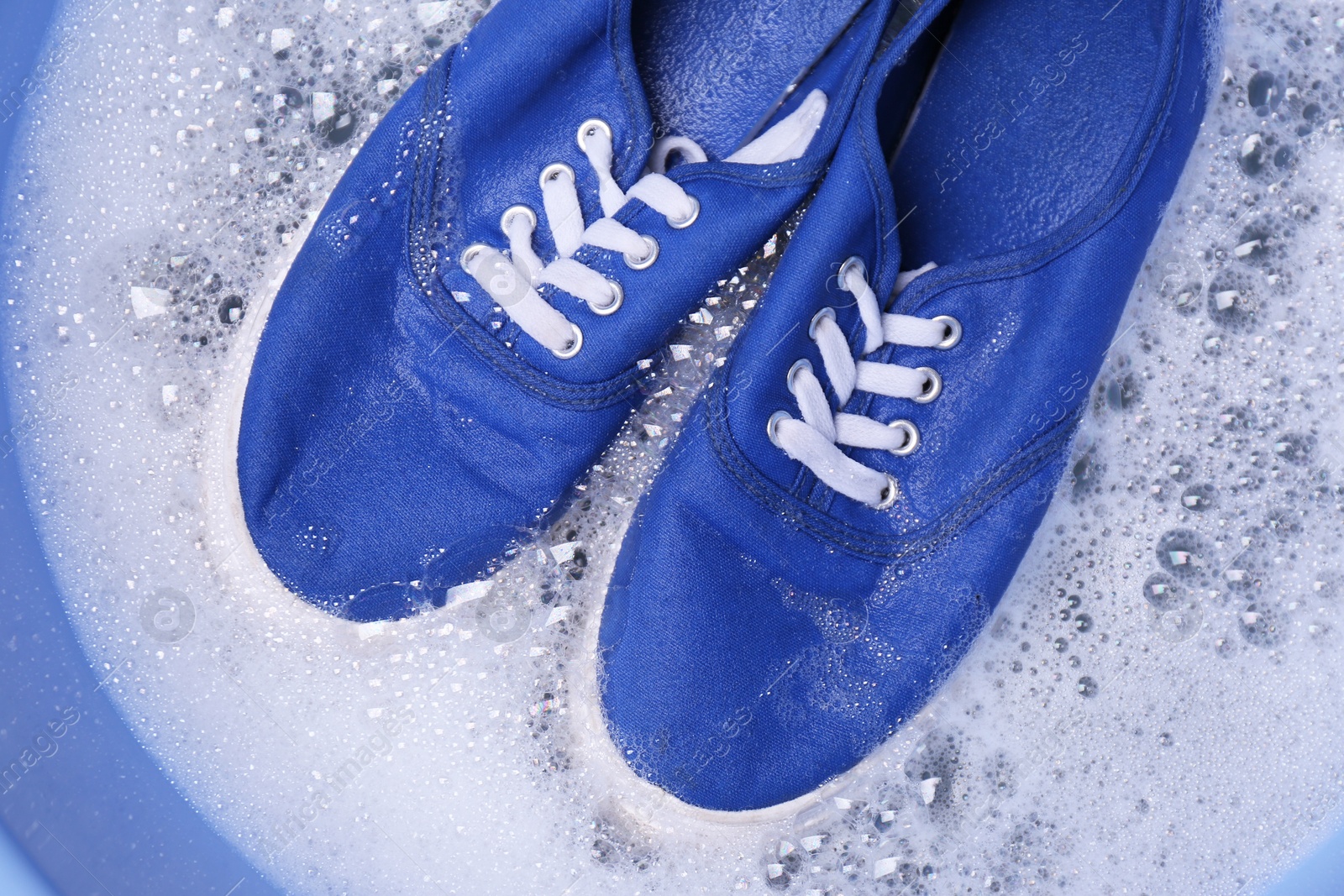 Photo of Washing sport shoes in plastic basin, top view