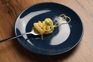 Photo of Heart made with spaghetti and fork on wooden table