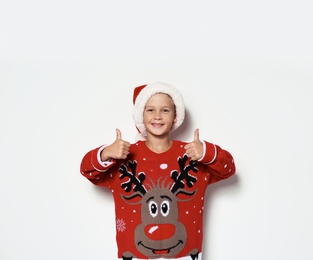 Photo of Cute little boy in Christmas sweater and hat on white background