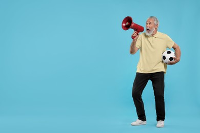 Photo of Emotional senior sports fan with soccer ball using megaphone on light blue background, space for text
