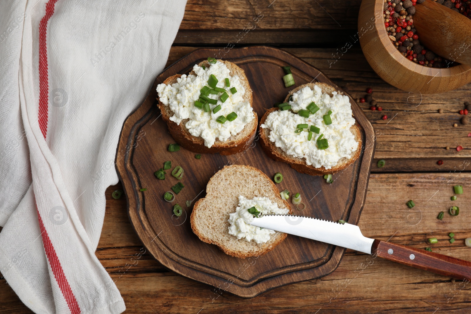 Photo of Bread with cottage cheese and green onion on wooden table, flat lay