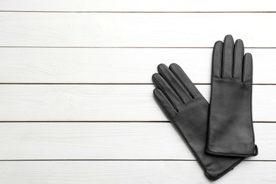 Photo of Stylish black leather gloves on white wooden background, flat lay. Space for text