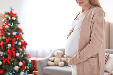 Photo of Happy pregnant woman in room decorated for Christmas