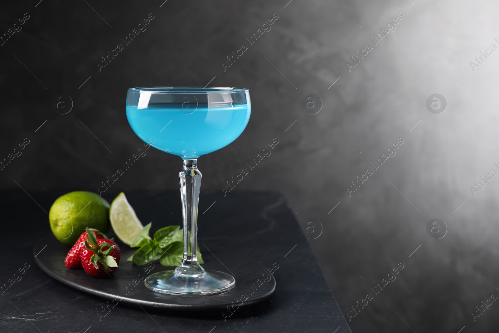 Photo of Light blue cocktail served on dark table, space for text