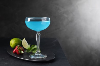 Photo of Light blue cocktail served on dark table, space for text