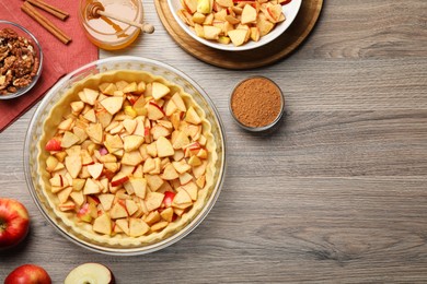 Photo of Flat lay composition with raw dough and ingredients for apple pie on wooden table
