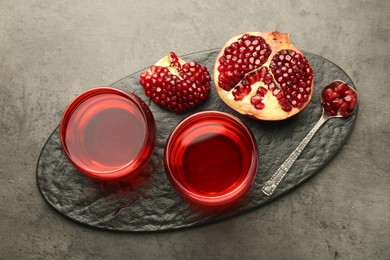 Photo of Tasty pomegranate juice in glasses and fresh fruit on grey table, top view
