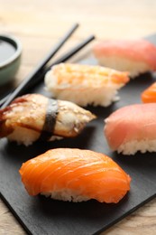 Photo of Serving board with delicious nigiri sushi and soy sauce on wooden table, closeup