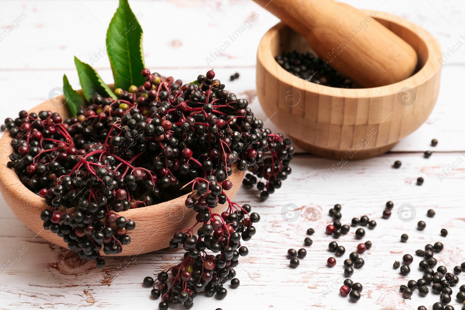 Photo of Tasty elderberries (Sambucus) on white wooden table