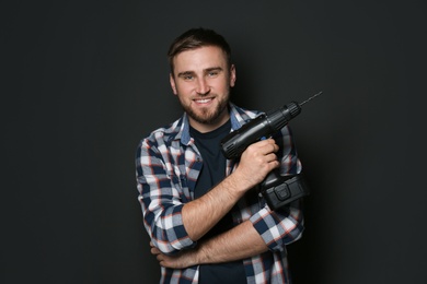 Photo of Young working man with power drill on dark background