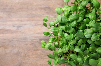 Photo of Fresh organic microgreen on wooden table, top view. Space for text