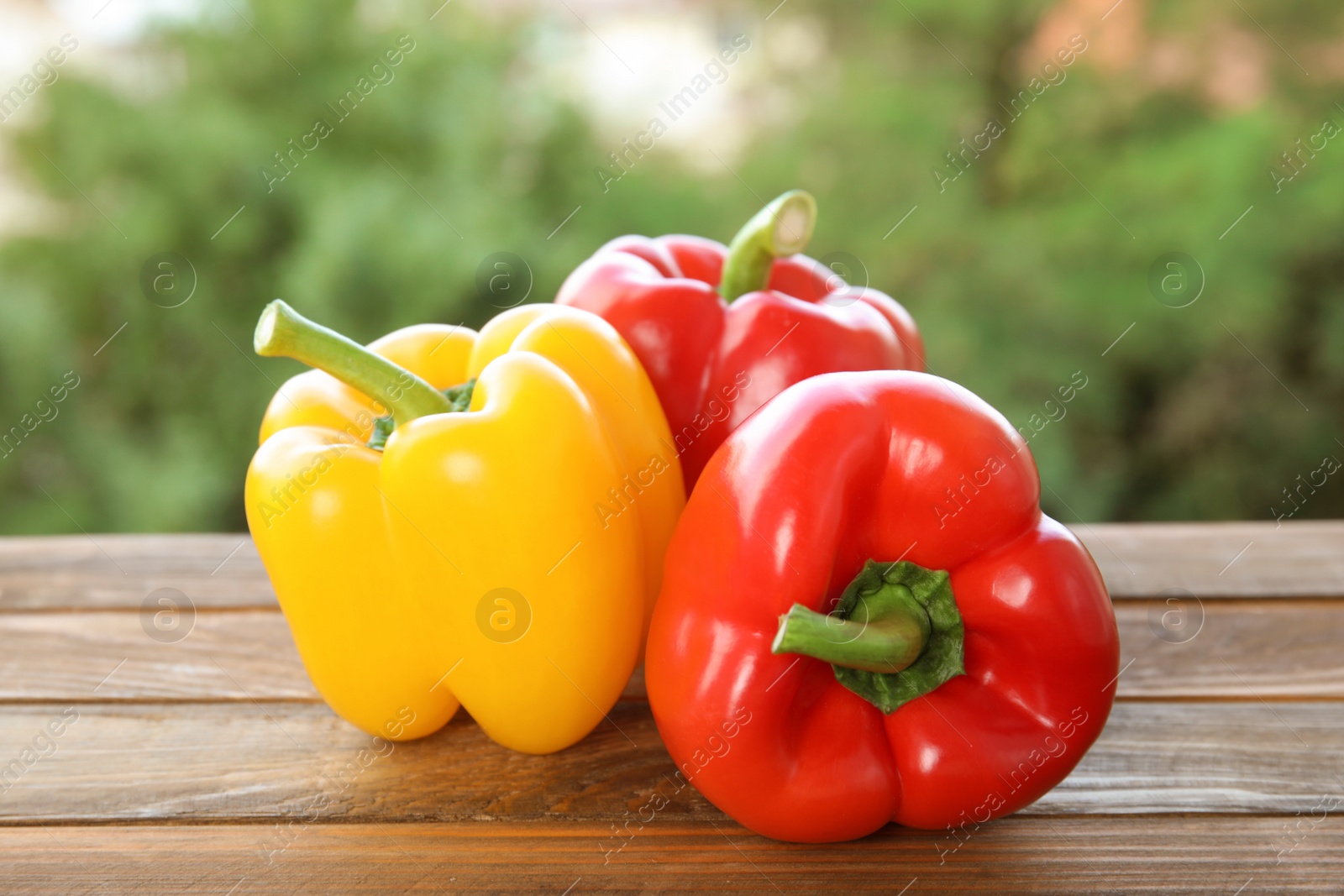 Photo of Raw ripe paprika peppers on table against blurred background