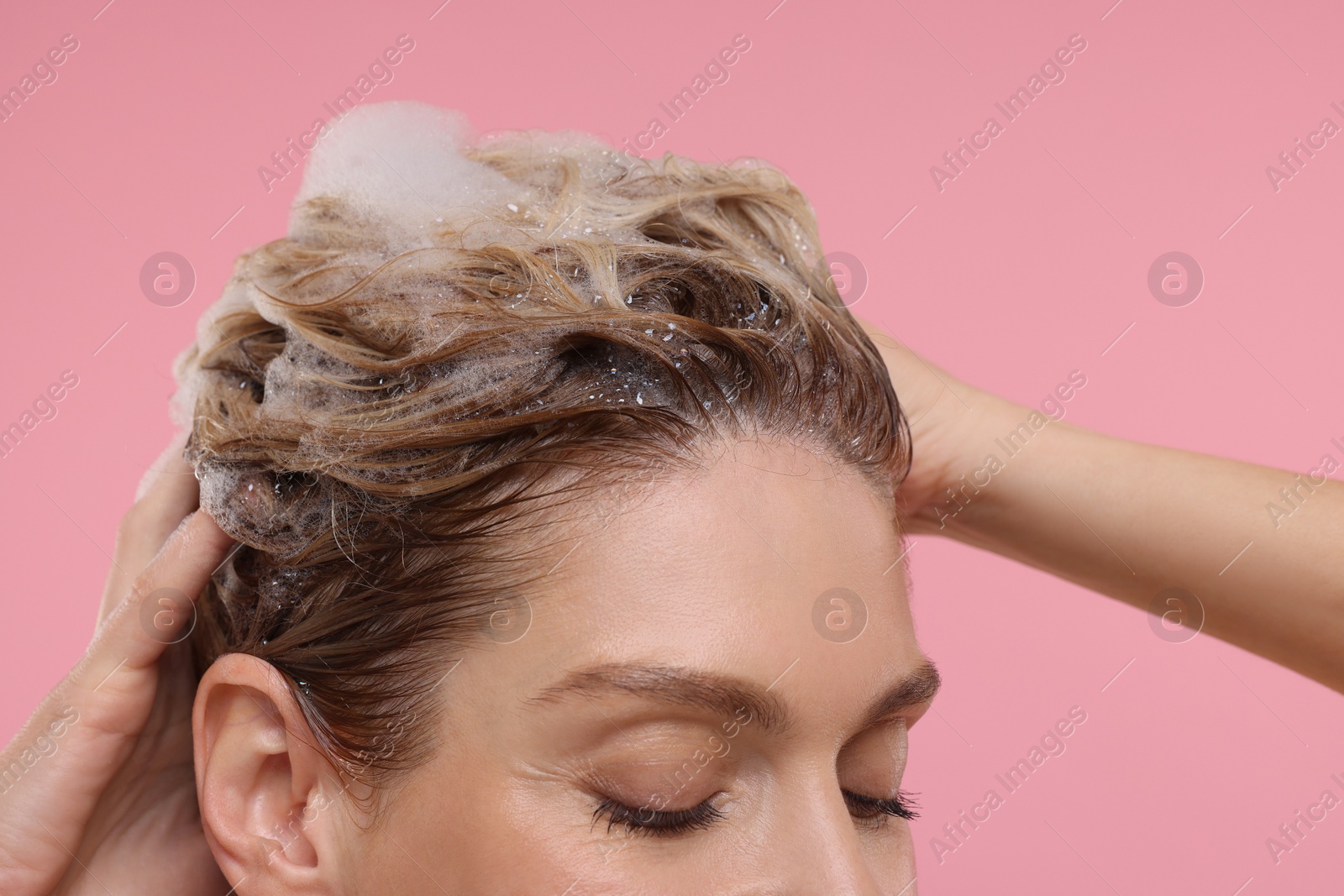 Photo of Woman washing hair on pink background, closeup