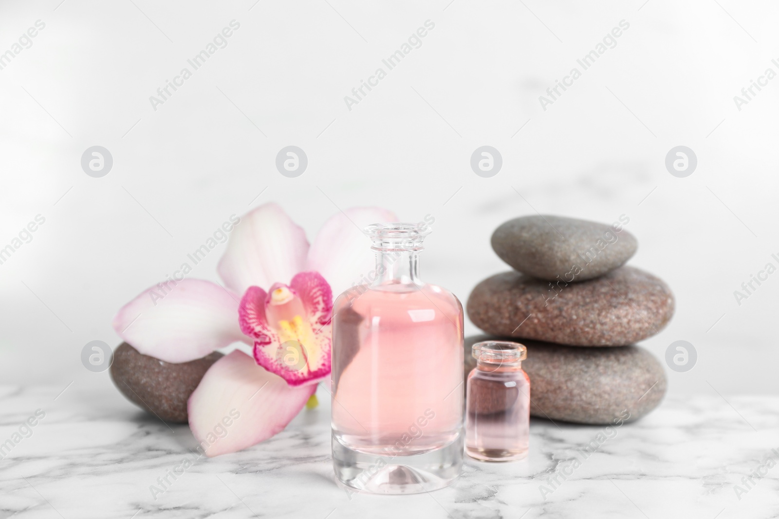 Photo of Beautiful composition with aroma oil and spa stones  on white marble table