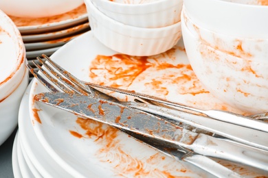 Stack of dirty dishes with cutlery, closeup