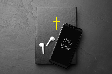 Photo of Bible, phone and earphones on black background, top view. Religious audiobook