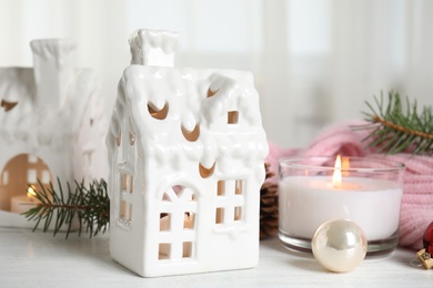 Composition with candles in house shaped holders on white wooden table. Christmas decoration