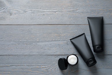 Photo of Tubes and jar with men's facial creams on grey wooden table, flat lay. Mockup for design