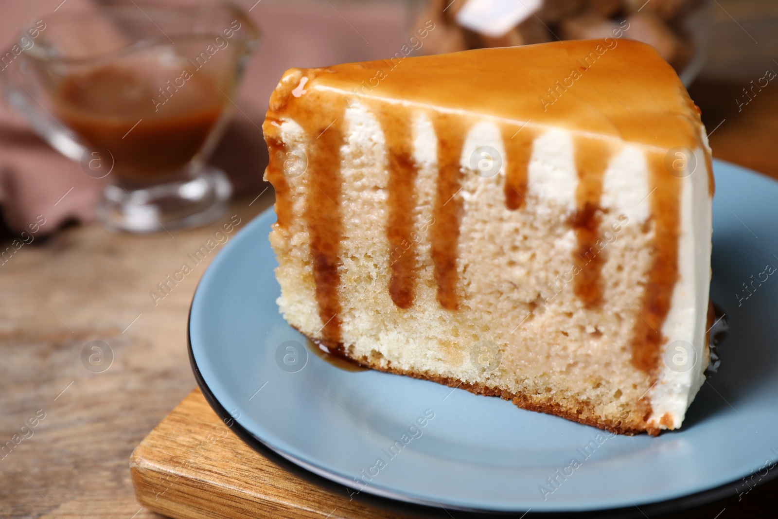 Photo of Slice of delicious cake with caramel sauce on wooden table, closeup