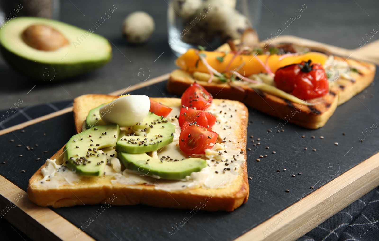 Photo of Toasts with avocado, cherry tomato, quail egg and chia seeds served on board