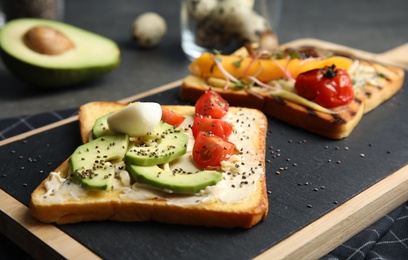 Toasts with avocado, cherry tomato, quail egg and chia seeds served on board