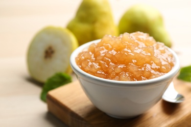 Photo of Tasty homemade pear jam and fresh fruits on wooden table, closeup