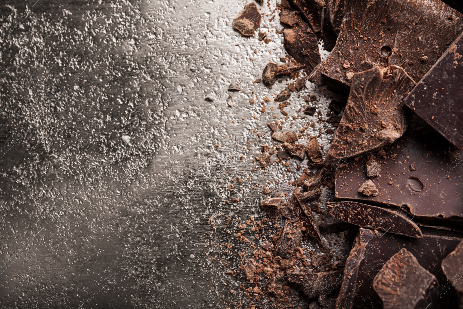 Photo of Pieces of dark chocolate on metal background, flat lay. Space for text