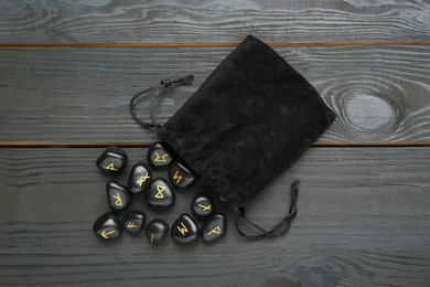 Bag with rune stones on black wooden table, flat lay