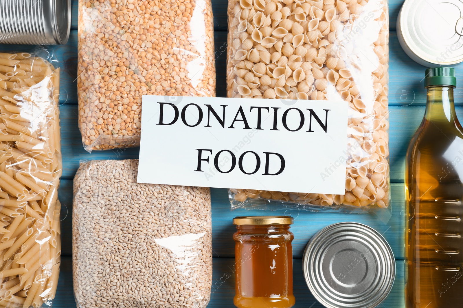 Photo of Card with words Donation Food and different products on turquoise wooden table, flat lay