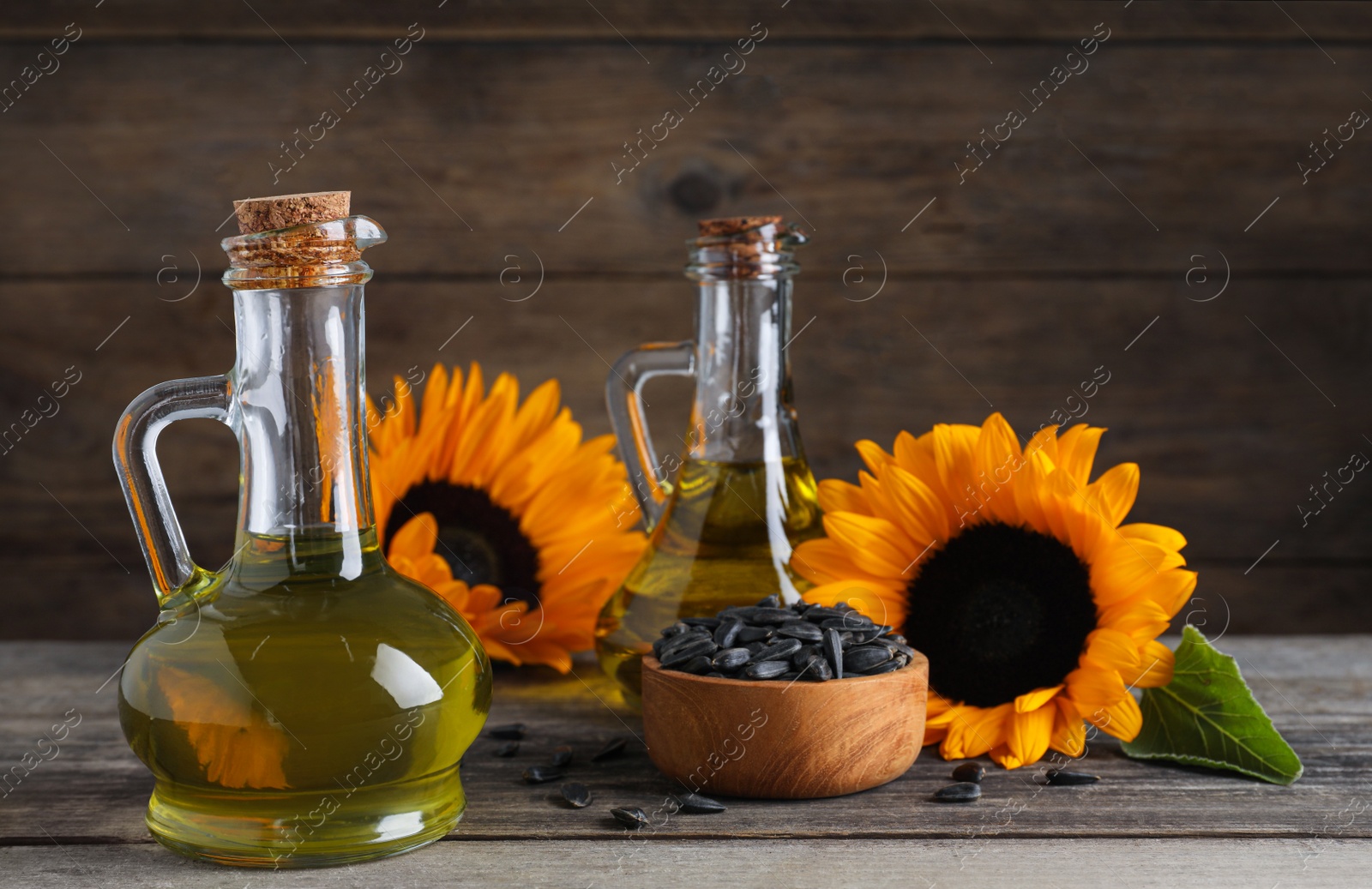 Photo of Sunflower cooking oil, seeds and yellow flowers on wooden table