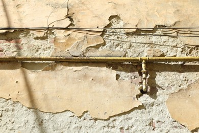 Photo of Rusty gas pipe on old wall outdoors