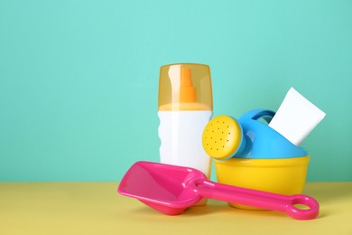 Photo of Different suntan products and plastic beach toys on color background. Space for text