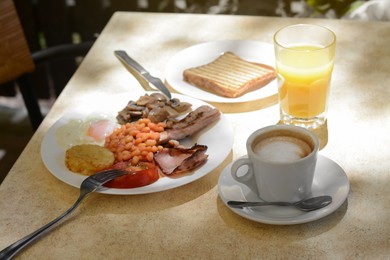 Delicious breakfast with fried meat and vegetables served on beige table