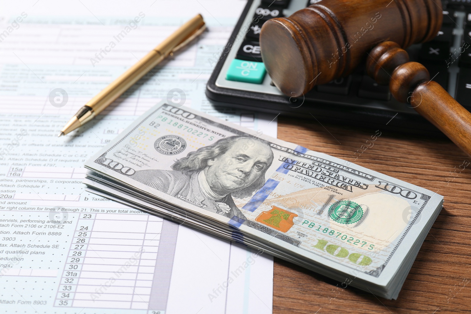 Photo of Tax return form, dollar banknotes, gavel, pen and calculator on wooden table, closeup