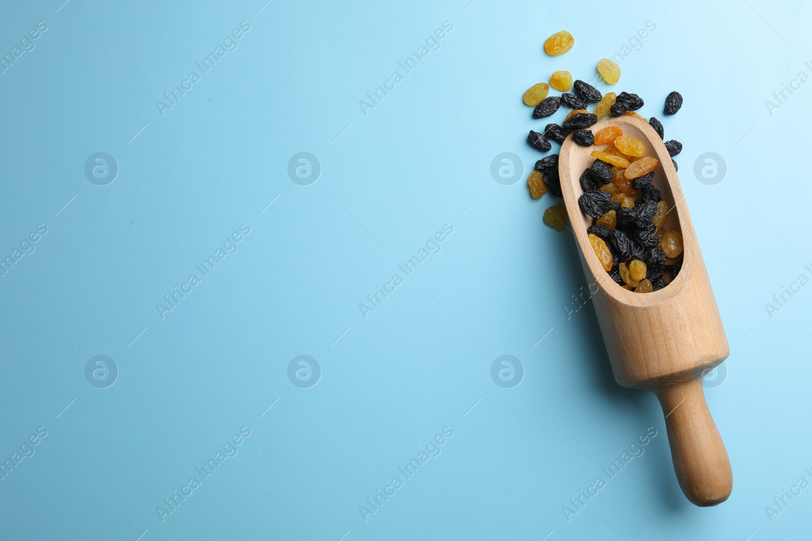 Photo of Scoop of raisins on color background, top view with space for text. Dried fruit as healthy snack