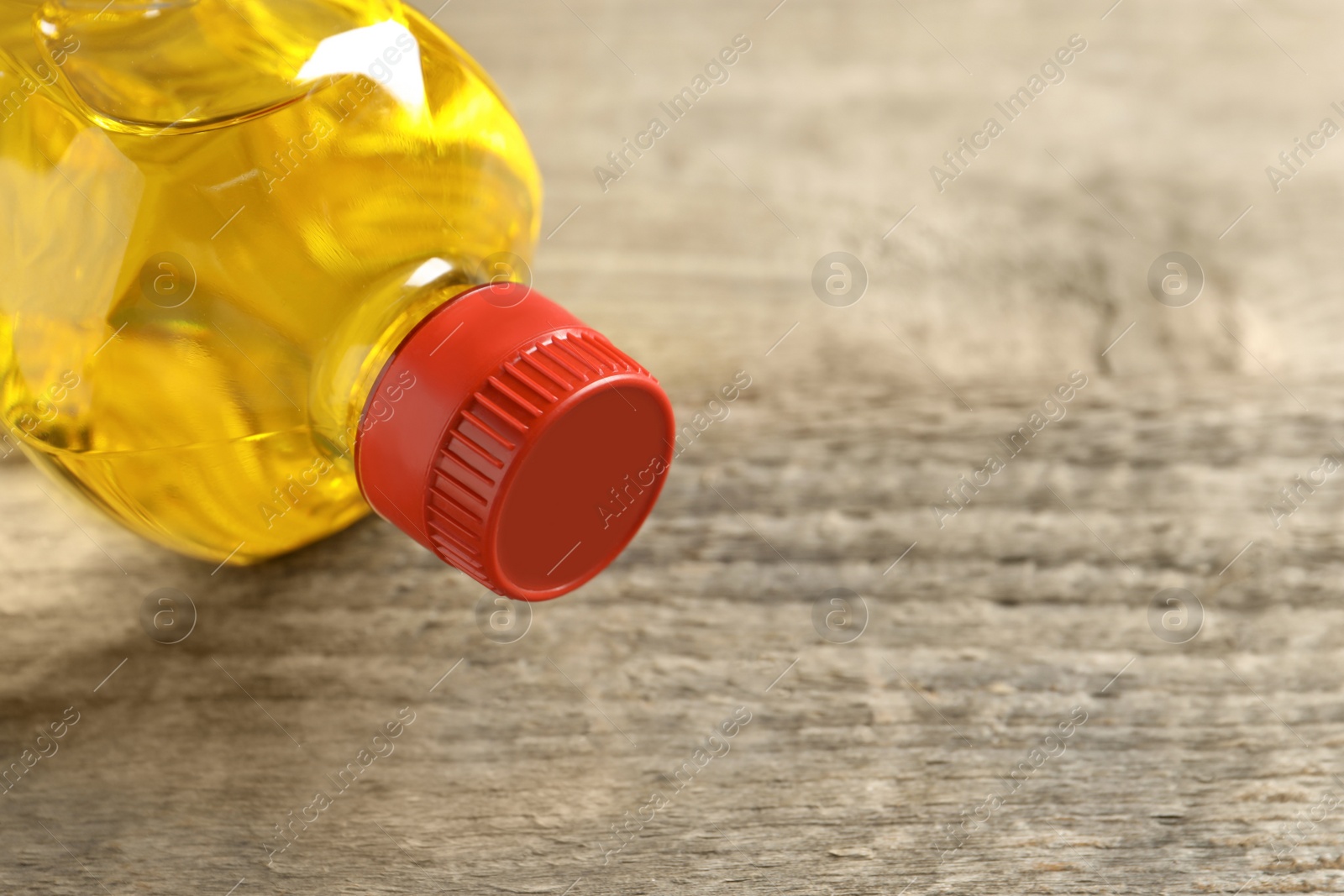 Photo of Plastic bottle of cooking oil on wooden table. Space for text