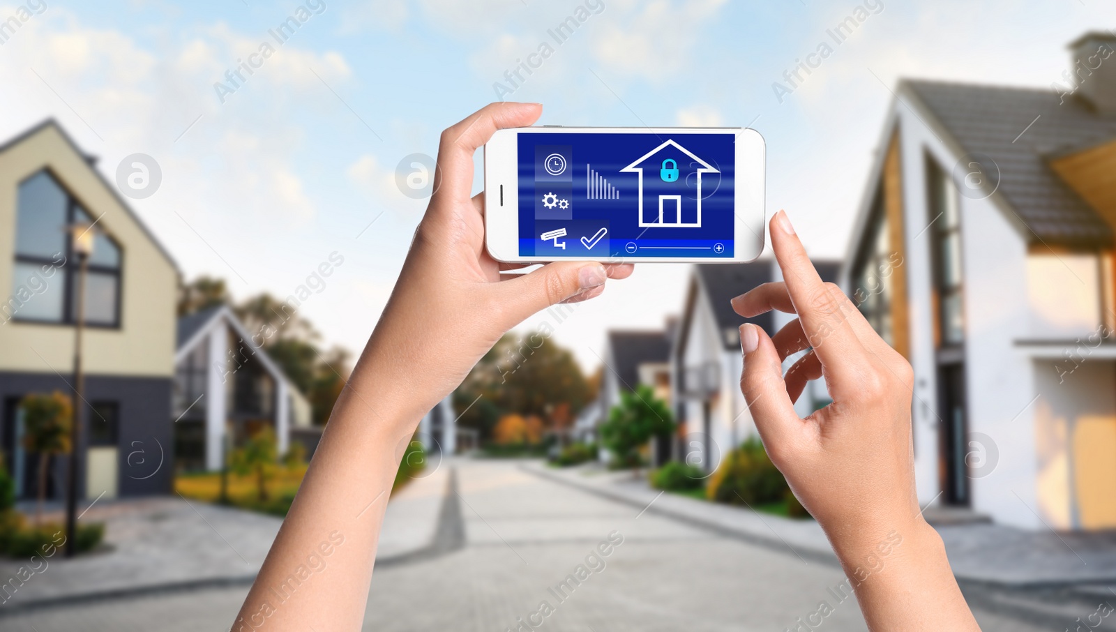 Image of Woman using home security app on smartphone outdoors, closeup