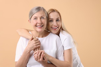 Photo of Family portrait of young woman and her mother on beige background