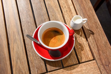 Photo of Cup of aromatic hot coffee and milk on wooden table, above view