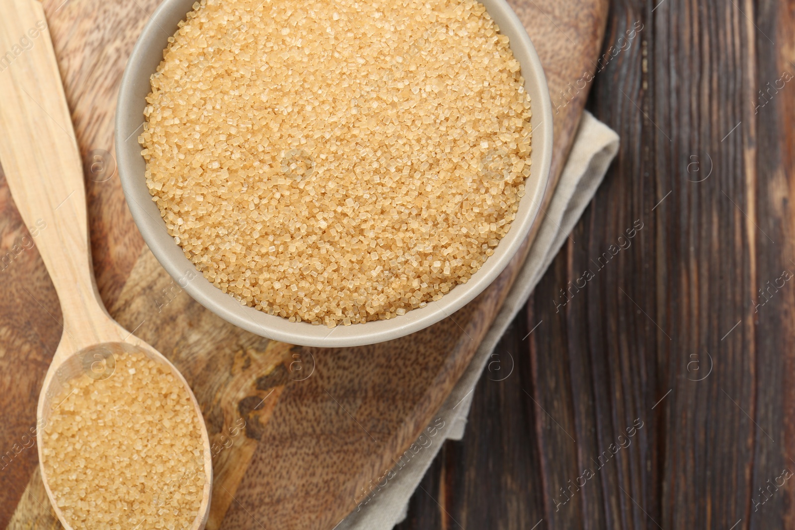 Photo of Brown sugar in bowl and spoon on wooden table, flat lay