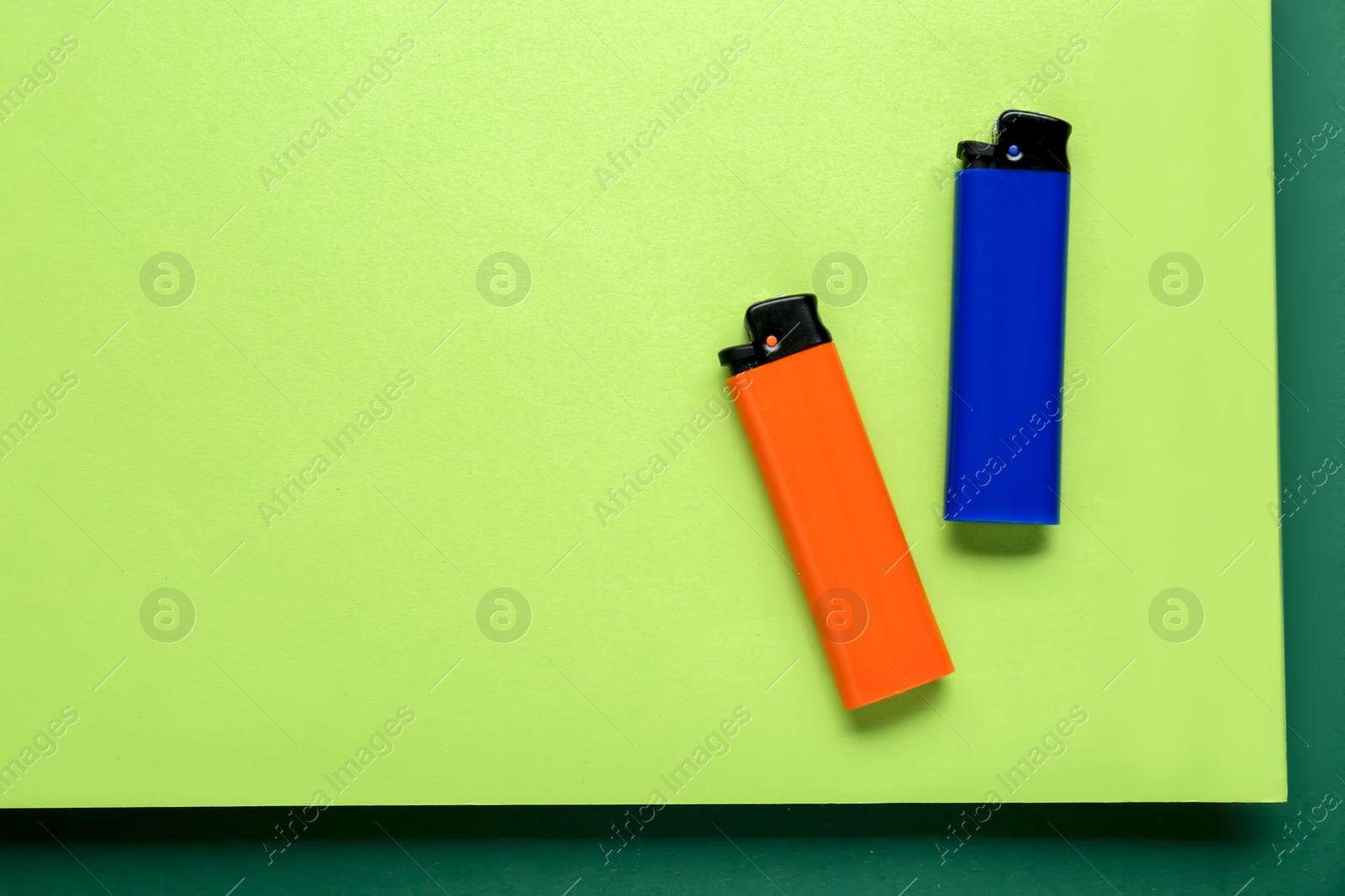 Photo of Stylish small pocket lighters on color background, flat lay. Space for text