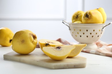 Photo of Tasty ripe quinces and metal colander on white wooden table