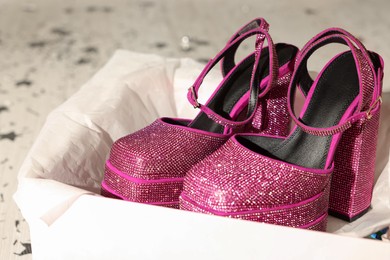 Photo of New pink high heeled shoes with platform and square toes in open box on floor, closeup
