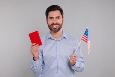 Immigration. Happy man with passport and American flag on gray background