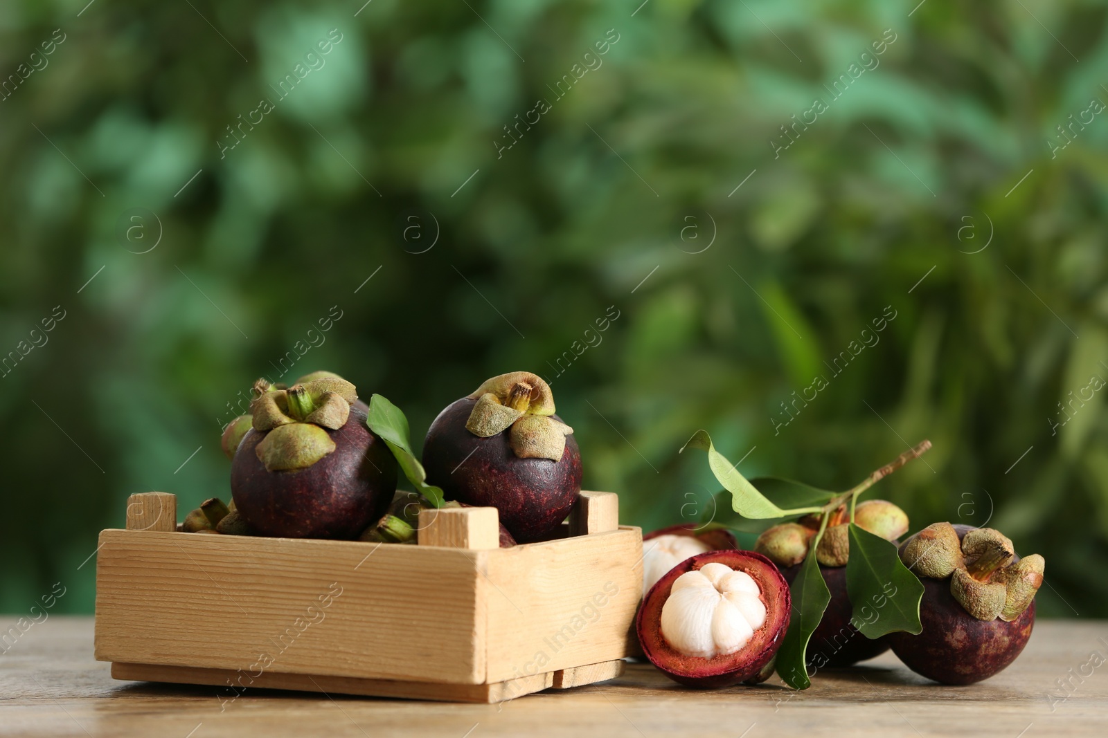 Photo of Delicious tropical mangosteen fruits on wooden table. Space for text