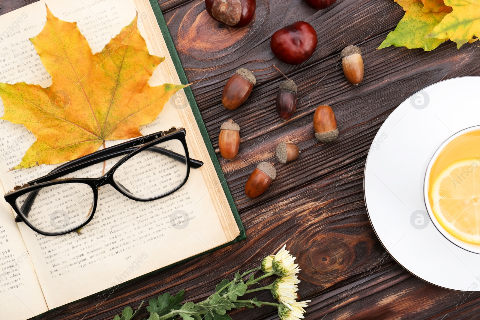 Photo of Maple leaves, book and cup of tea on wooden table, flat lay. Autumn atmosphere