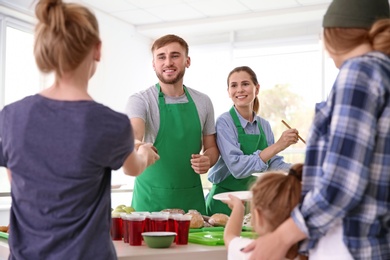 Volunteers serving food for poor people indoors